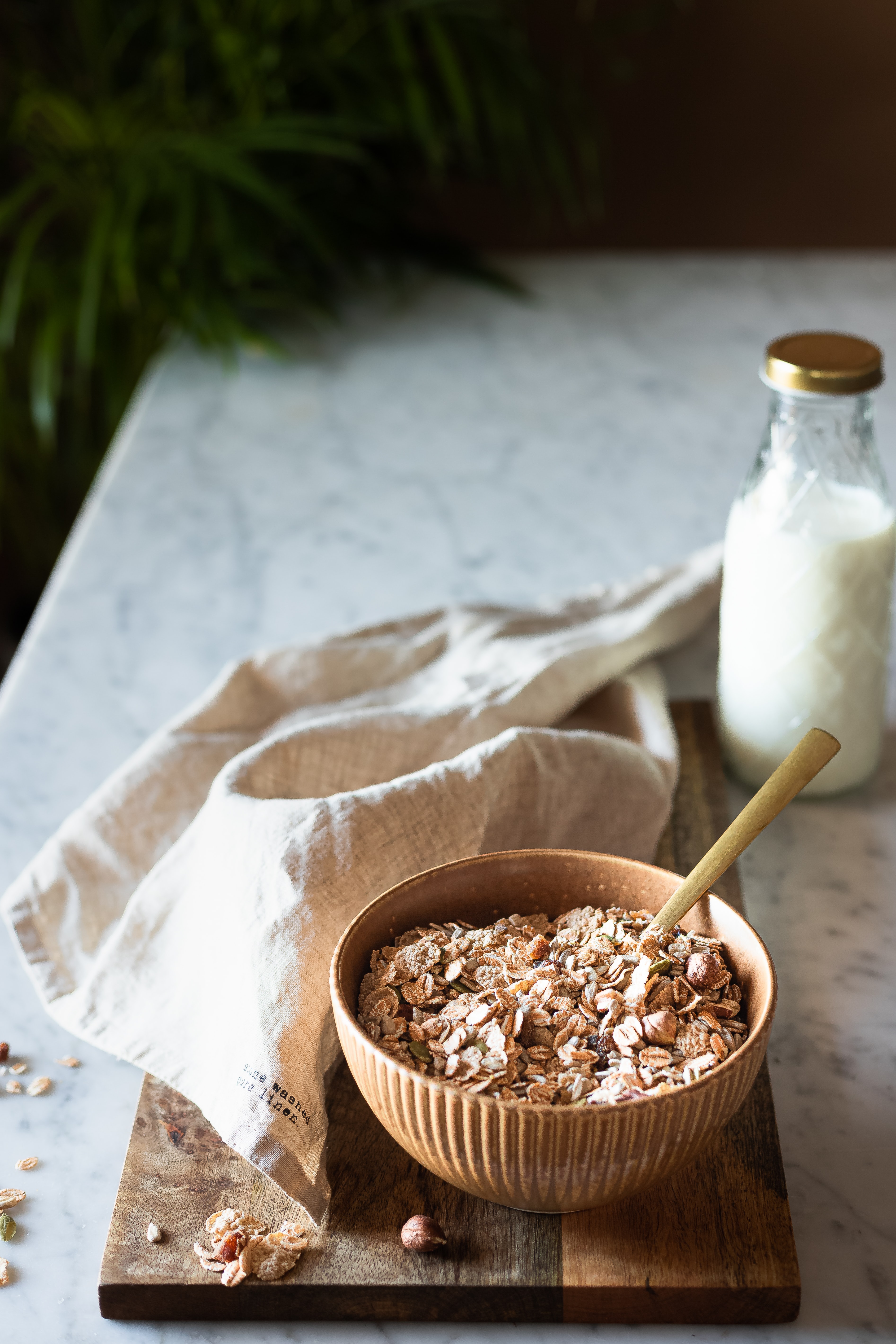 a bowl of oats is sat on a marble work surface next to a tea towel and a glass bottle of milk
